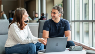 Une étudiante et un étudiant discutent assis à une table à café