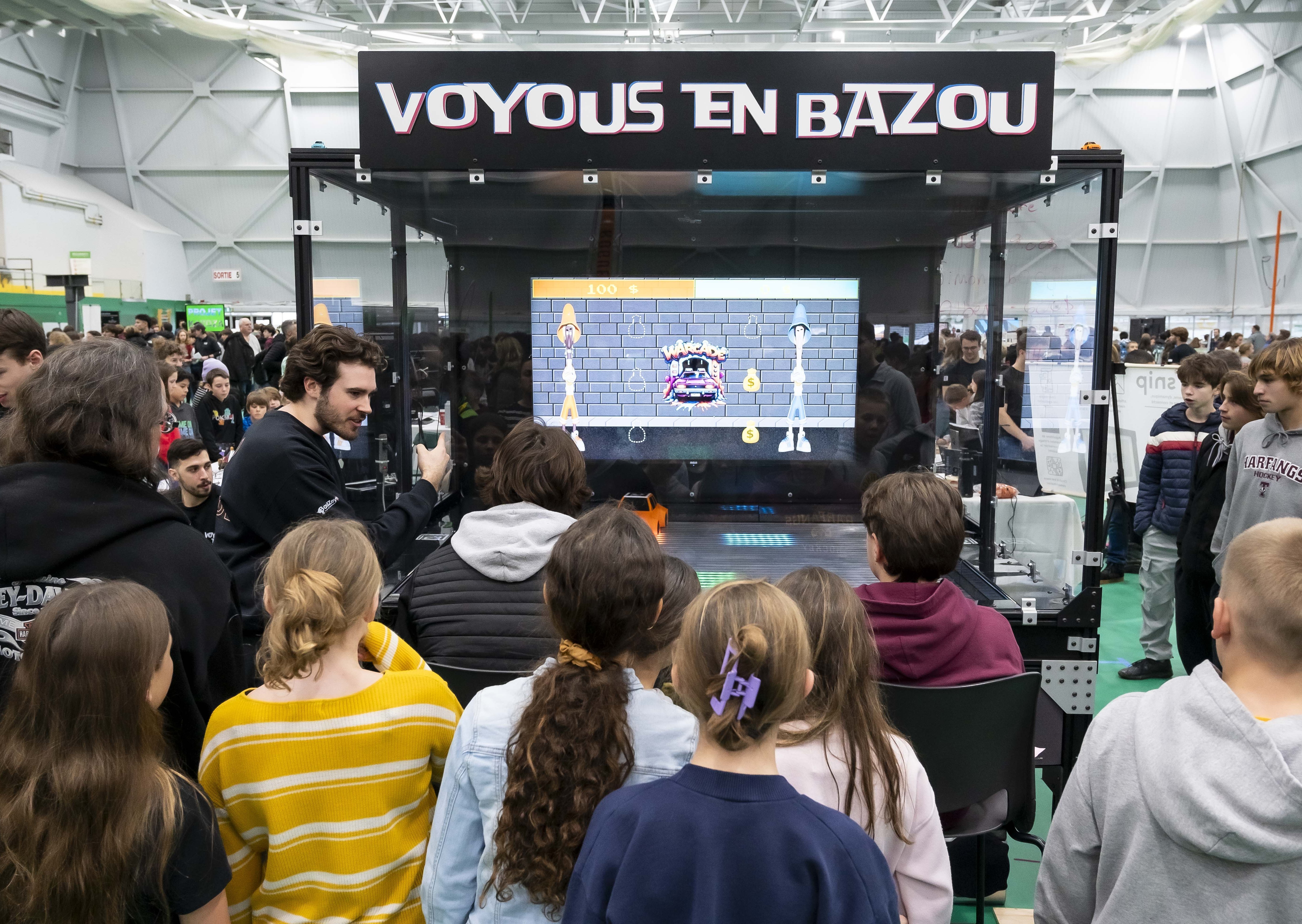 Enfants de dos jouant à un jeu d'arcade à la l'Expo MégaGÉNIALE