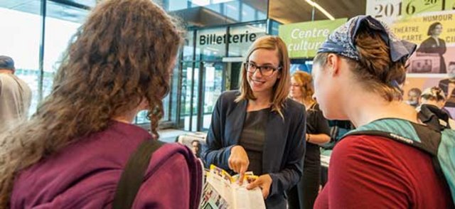 Dans le hall du Centre culturel, une étudiante-em ployée donne de l'information à deux personnes