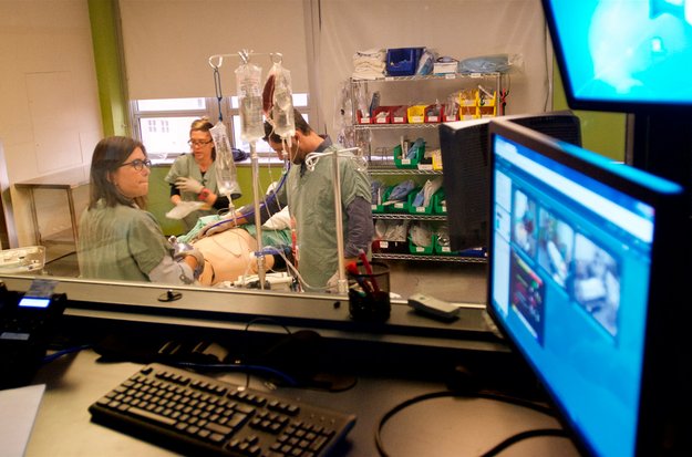 Personnes étudiantes et enseignantes dans un laboratoire de simulation clinique autour d’un mannequin sur une civière.