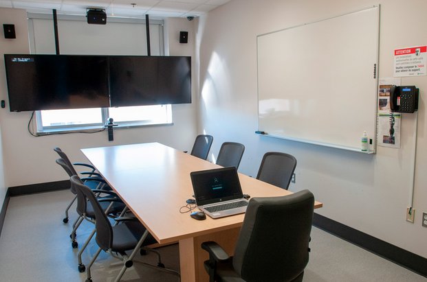 Salle de travail avec une table de conférence et un écran. 