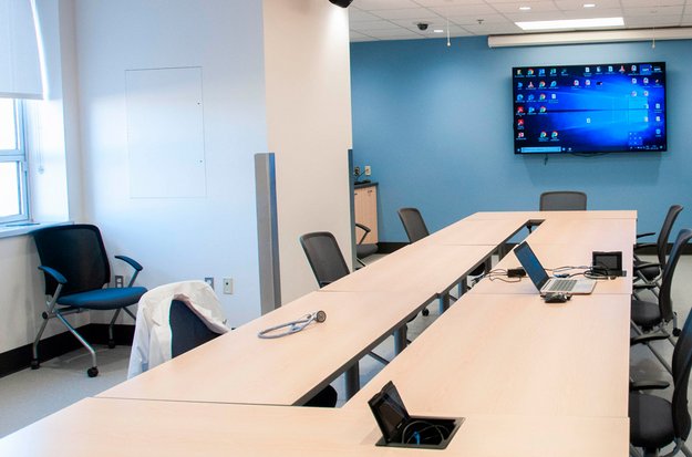 Salle de travail avec une grande table de conférence et un écran. 