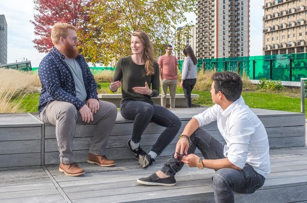 Personnes qui discutent dans une aire de détente située sur le toit vert du Campus de Longueuil de l’Université de Sherbrooke.