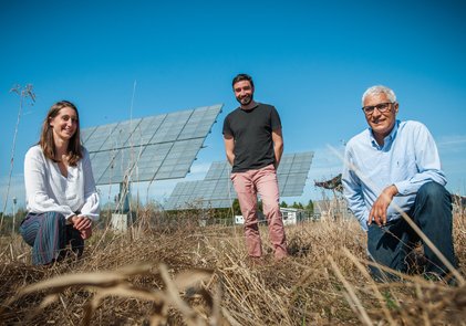 Trois personnes dans un champ devant des panneaux solaires