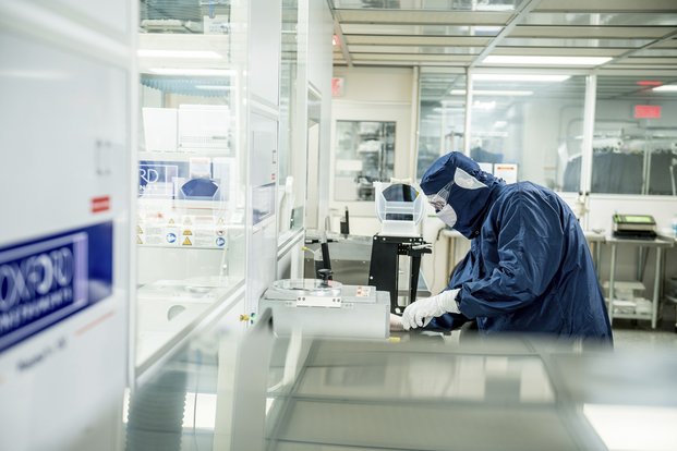 Personne portant un habit bleu de la tête aux pieds et travaillant dans un laboratoire aseptisé.