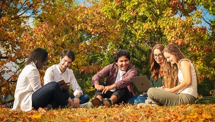 Étudiants avec ordinateurs dans les feuilles d'automne