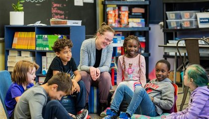 Enseignante assise entourée de ses élèves qui discutent