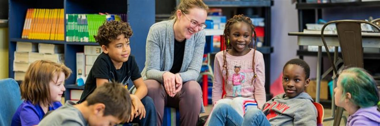 Enseignante assise et entourée d'enfants