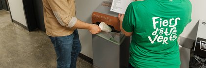 Jeune homme déposant un verre compostable dans un bac de tri