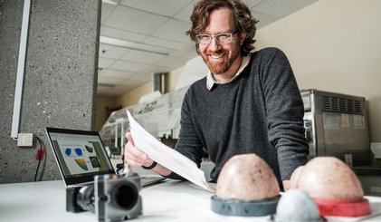 Photo du Pr Elijah Van Houten devant des prototypes de soutiens-gorge