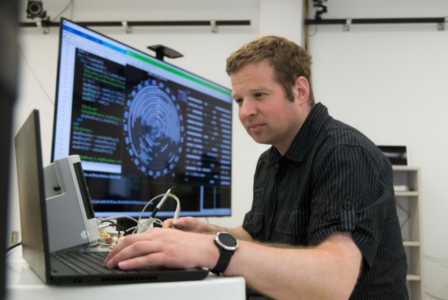 Un homme qui manipule un instrument faisant partie d'un logiciel présenté sur un écran à côté de lui.