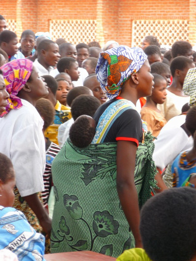 Une dame à l'église avec son enfant sur le dos.